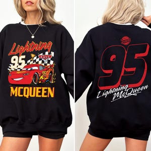 Puede incluir: Sudadera negra con dise&ntilde;o de Rayo McQueen de la pel&iacute;cula Cars. El frente muestra "Lightning 95 McQueen" y un coche de carreras rojo. La parte trasera tiene un gran "95" rojo y "Lightning McQueen" en blanco.