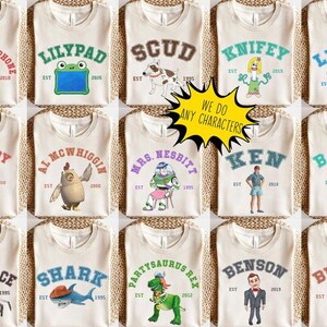 May include: A collection of beige t-shirts featuring various cartoon characters and names in collegiate-style lettering. Each shirt has a different character, such as "Chatter Telephone," "Lilypad," and "Scud." The shirts also include the text "We do any characters."