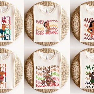 May include: Six cream-colored t-shirts with various character designs from the movie Moana. Each shirt features a different character with their name. The shirts are displayed on round, woven placemats.