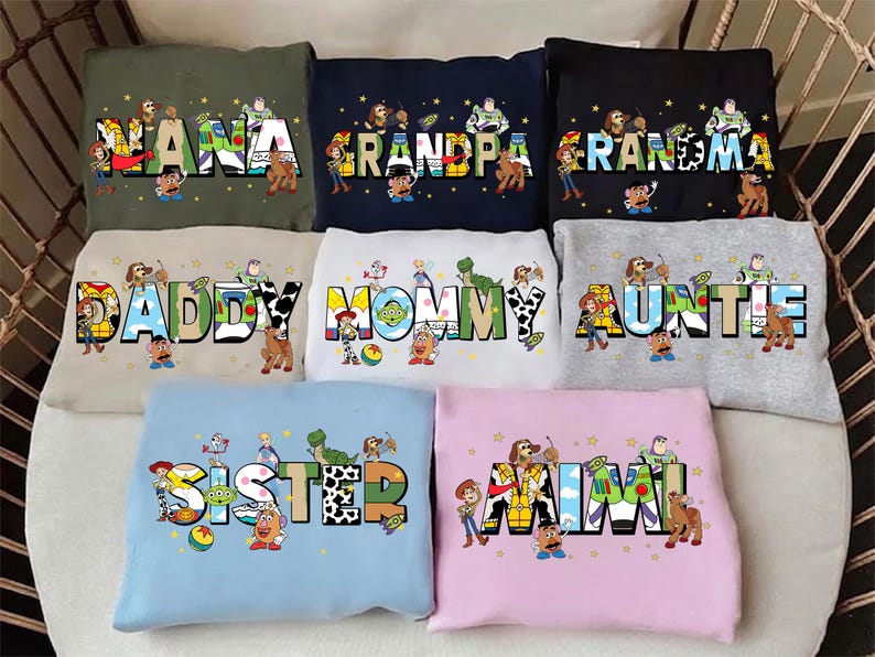May include: A collection of colorful sweatshirts featuring characters from a popular animated movie. Each sweatshirt displays a different family title, such as "NANA", "GRANDPA", "MOMMY", and "AUNTIE", with the characters integrated into the lettering.