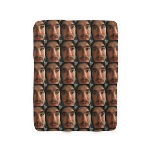 May include: A fleece blanket featuring a repeating pattern of a person's face. The faces are arranged in a grid, creating a unique and eye-catching design. The blanket is likely soft and cozy.