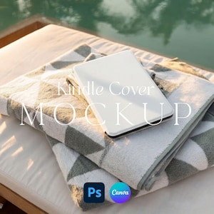 May include: A white Kindle cover rests on a folded geometric patterned towel. The towel is white, gray, and green. The text "Kindle Cover MOCKUP" is overlaid on the image. The background shows a pool and a white cushioned surface.