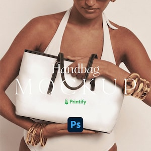 Può includere: Borsa bianca con manici e finiture nere. La borsa è tenuta da una persona che indossa un top bianco all'americana e braccialetti dorati. Il testo "handbag MOCKUP" è visualizzato sulla borsa.