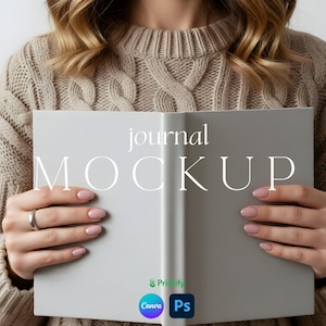 以下が含まれることがあります： 「journal MOCKUP」の文字が表示された、開かれた灰色のジャーナルのモックアップ。ベージュのケーブルニットのセーターを着た人がジャーナルを持っています。ジャーナルはクリーンでミニマリストなデザインで、右下にCanvaとPsのロゴがあります。