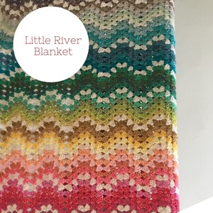 May include: A colourful crochet blanket with a gradient of colours from blue to green to yellow to orange to red to purple. The blanket is made with a simple stitch pattern and has a fringed edge. The text "Little River Blanket" is visible in the image.