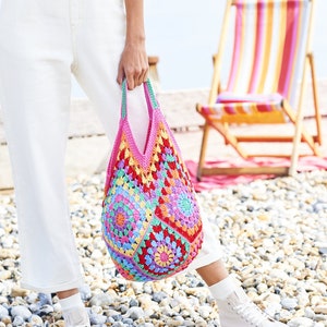 May include: A colorful crocheted tote bag with a pink, red, yellow, green, and blue pattern. The bag is made of yarn and has a square shape.