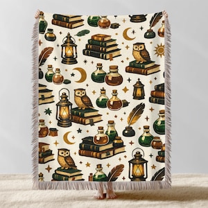 May include: A cream-colored throw blanket with a repeating pattern of owls, books, lanterns, potion bottles, feathers, moons, and stars. The blanket has a fringed edge and is made of a soft material.