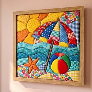 May include: A square fabric wall art piece in a light wood frame featuring a quilted beach scene. The design includes a yellow sun, a multi-colored patterned beach umbrella, blue wavy ocean fabric, an orange starfish, and a round beach ball.