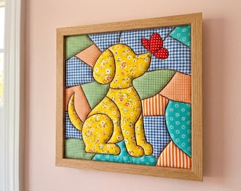 May include: A square framed fabric wall art piece featuring a yellow floral dog appliqué looking at a red butterfly. The background is composed of various quilted fabric patches in blue gingham, green checkered, and orange striped patterns.