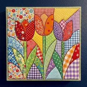 May include: A square fabric wall hanging featuring a pieced quilt design of three tulips. The flowers and leaves are constructed from various cotton fabrics in red, orange, yellow, purple, and green, showcasing floral, gingham, and polka dot patterns.