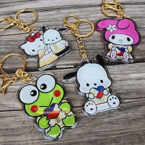 May include: Four acrylic keychains featuring Sanrio characters including Hello Kitty, Pochacco, My Melody, and Keroppi. Each character wears traditional Filipino clothing and holds a heart with the Philippine flag design. Gold-tone metal rings.
