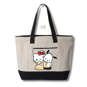 May include: A beige tote bag with black accents and handles. The bag features a zippered pocket and a graphic of Hello Kitty and Pochacco in traditional attire. The bag is designed with a black bottom.