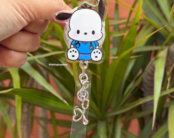 May include: A clear acrylic badge reel featuring a cartoon dog character wearing a blue medical scrub top and a stethoscope. The badge reel includes a silver-toned metal lobster clasp attached to a clear plastic strap with a small silver stethoscope charm.