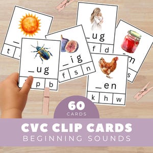 May include: A collection of CVC clip cards for beginning sounds. The cards feature watercolor illustrations of a sun, bug, fig, mother and child, jar of jam, and a chicken. The cards are white with black text and are held together with wooden clothespins.