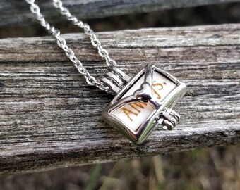 May include: Silver necklace with a small silver envelope charm that says "Always" on it.
