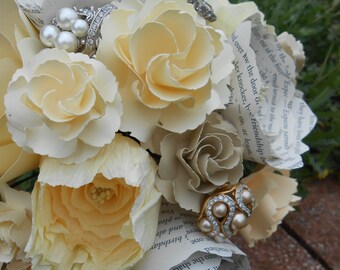 May include: A bouquet of cream-colored paper flowers with a vintage book page background. The bouquet is decorated with pearl and rhinestone jewelry.