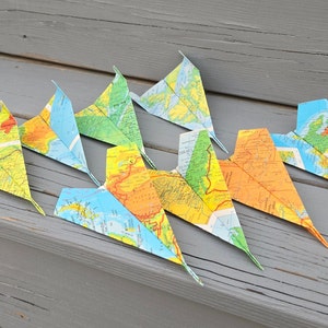 Kaart papieren vliegtuigen. Verjaardagsversieringen, bruiloftsconfetti, kaartvliegtuigen, origamivliegtuigen. Bruiloftsdecoraties, plaatskaarten