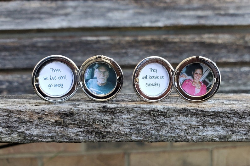 May include: Two silver locket style photo frames with a hinged lid. The locket on the left has a photo of an older man and the text "Those we love don't go away". The locket on the right has a photo of a woman and the text "They walk beside us everyday".
