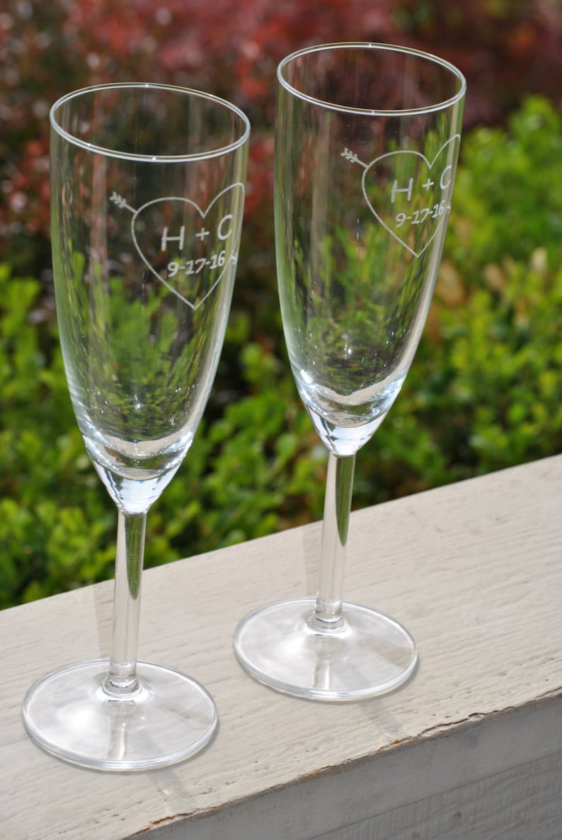 May include: Two clear glass champagne flutes with etched hearts and the initials H+C and the date 9-27-16.