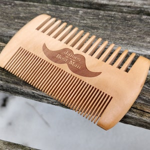 Peut inclure: Un peigne en bois avec un motif de moustache et le texte "James - Best Man" grav&eacute; dessus.