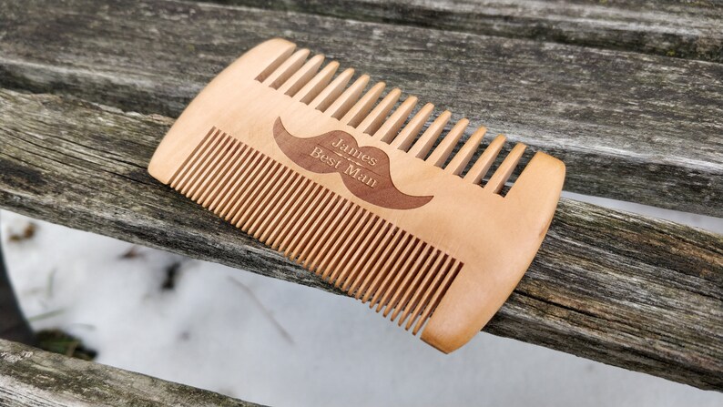 Peut inclure: Un peigne en bois avec un motif de moustache et le texte "James - Best Man" grav&eacute; dessus.