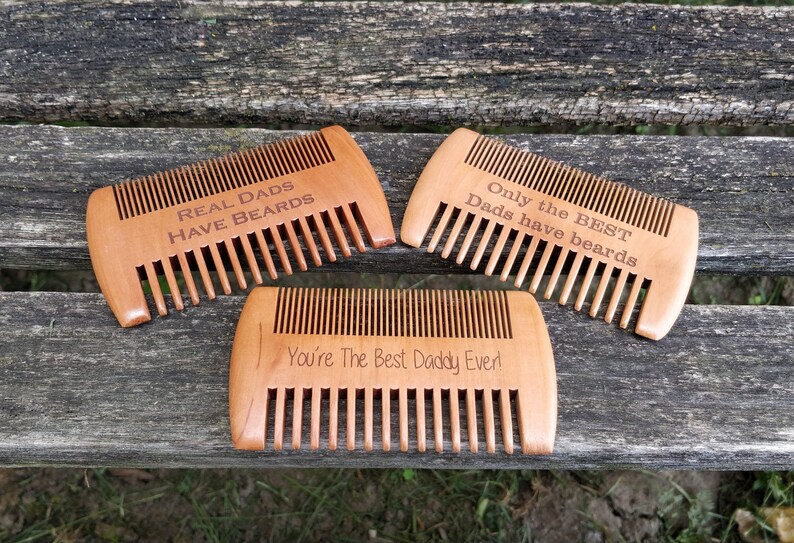 Peut inclure: Trois peignes en bois avec des messages grav&eacute;s. Le premier peigne porte l'inscription "Real Dads Have Beards". Le deuxi&egrave;me peigne porte l'inscription "Only the Best Dads Have Beards". Le troisi&egrave;me peigne porte l'inscription "You're The Best Daddy Ever!"