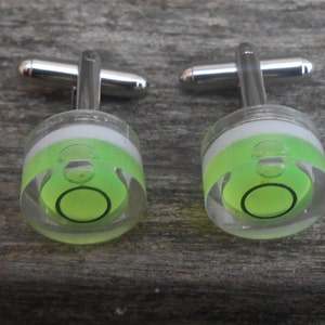 Può includere: Un paio di gemelli d'argento con un design a bolla di livello verde e bianco.
