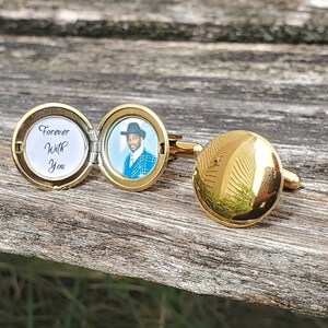 May include: Gold cufflinks with a round, hinged locket. The locket opens to reveal a black and white photo of a man wearing a hat and a blue patterned shirt. The inscription on the locket reads "Forever With You".