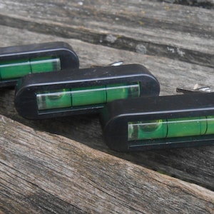 May include: Three black level tools with green bubble levels. The tools are designed to be attached to a surface.
