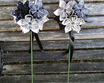 Puede incluir: Dos ramos de flores de origami en blanco y negro con tallos de cinta negra. Las flores están hechas de papel y tienen un diseño estampado en blanco y negro.