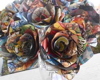 Puede incluir: Un ramo de rosas de papel hechas a mano a partir de páginas de cómics. Las rosas están dispuestas en un jarrón y presentan una variedad de personajes de cómics coloridos.