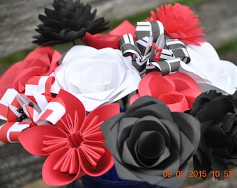 Puede incluir: Un ramo de flores de papel en negro, blanco y rojo. Las flores están dispuestas en un jarrón e incluyen rosas, lirios y otros tipos.