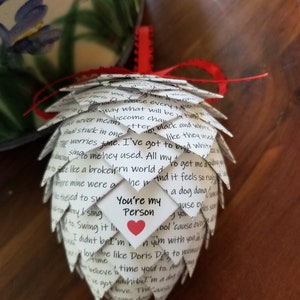 Pode incluir: Um enfeite de papel branco em forma de pinha com um cora&ccedil;&atilde;o vermelho e o texto "You're my Person" escrito nele. O enfeite &eacute; decorado com texto escrito &agrave; m&atilde;o.