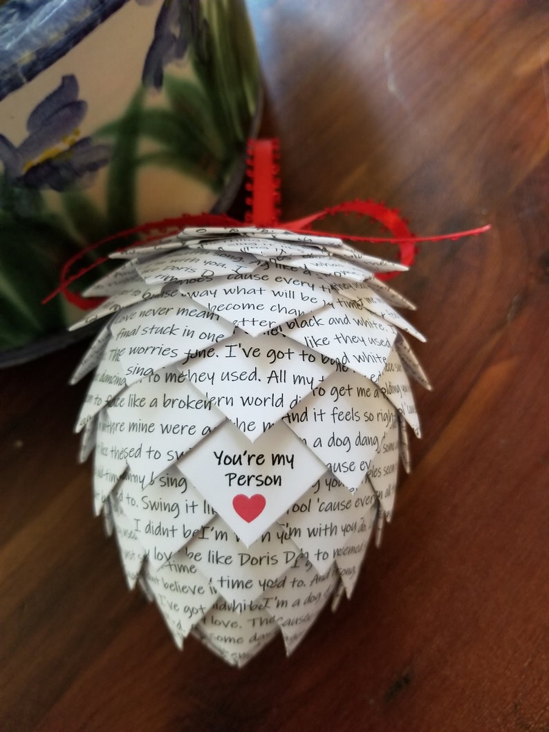 Pode incluir: Um enfeite de papel branco em forma de pinha com um cora&ccedil;&atilde;o vermelho e o texto "You're my Person" escrito nele. O enfeite &eacute; decorado com texto escrito &agrave; m&atilde;o.