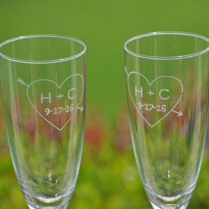 May include: Two clear glass champagne flutes with etched hearts and the initials H+C and the date 9-17-16.