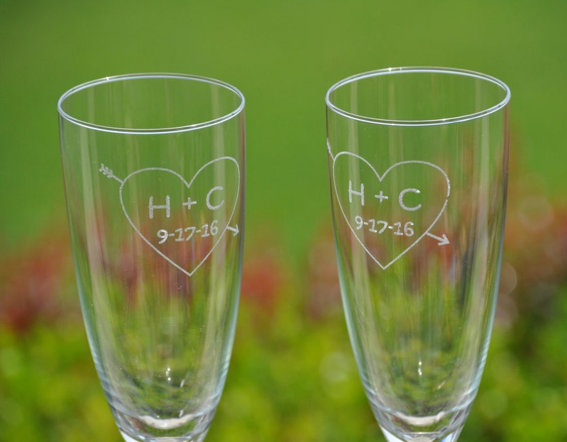 May include: Two clear glass champagne flutes with etched hearts and the initials H+C and the date 9-17-16.
