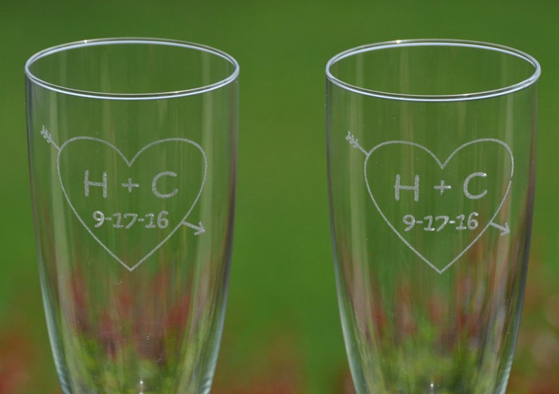 May include: Two clear glass champagne flutes with etched hearts and the initials H+C and the date 9-17-16.