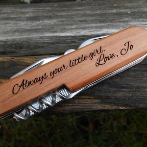 Könnte beinhalten: Ein Taschenmesser mit einem Holzgriff, graviert mit der Aufschrift "Always your little girl. Love, Jo".