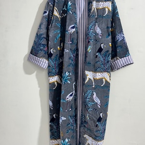 May include: A long-sleeved robe in a dark gray hue featuring a repeating pattern of leopards, toucans, and tropical foliage in white, yellow, and blue. The garment has an open front design with a vertical striped lining visible along the inner edges.