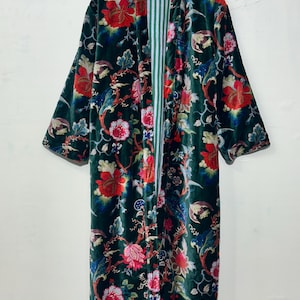 May include: A long-sleeved velvet robe in a deep forest green featuring a vibrant floral pattern with red, pink, and blue blossoms and winding stems. The interior lining displays a vertical white and green striped design throughout the garment.