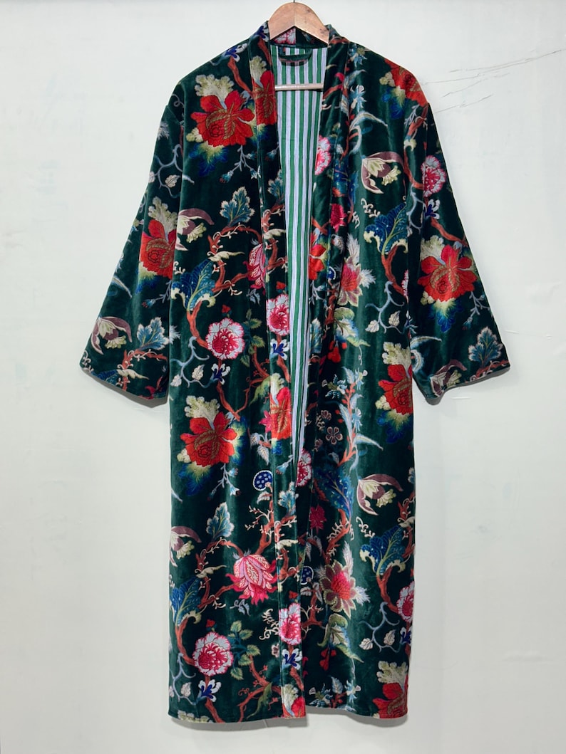 May include: A long-sleeved velvet robe in a deep forest green featuring a vibrant floral pattern with red, pink, and blue blossoms and winding stems. The interior lining displays a vertical white and green striped design throughout the garment.