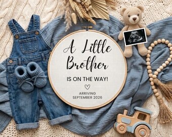 May include: A round embroidery hoop with white fabric featuring the text A Little Brother IS ON THE WAY! with a heart and ARRIVING SEPTEMBER 2026. Includes blue denim overalls, blue knit booties, a tan teddy bear with an ultrasound, and a wooden toy train.
