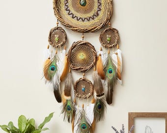 May include: A handcrafted dreamcatcher with a woven rattan frame and intricate web design. It features peacock feathers, beads, and smaller dreamcatchers hanging below. The color palette includes natural tones, brown, and teal.