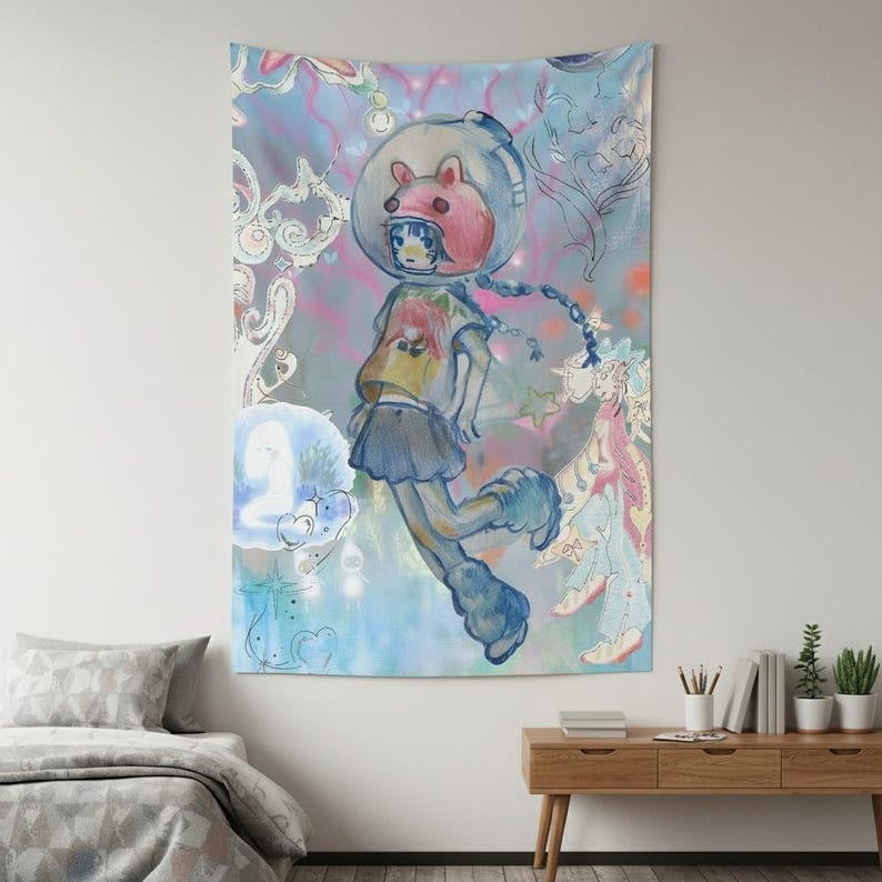 Op de afbeelding: Een groot wandtapijt met een grillige illustratie van een figuur in een ruimtehelm met een roze beerachtig ontwerp. De figuur draagt een geel shirt, een blauwe rok en blauwe laarzen, tegen een kleurrijke, dromerige achtergrond.