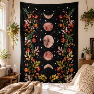 May include: A black wall tapestry featuring a vertical sequence of five moon phases in the center, surrounded by climbing floral vines with red and orange flowers, green leaves, and white butterflies against a starry night sky background.