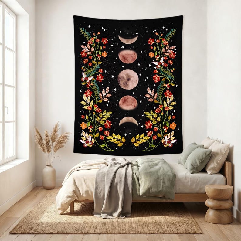 May include: A rectangular wall tapestry featuring a black background with a vertical sequence of five moon phases in the center. The design is framed by two symmetrical climbing floral vines with red flowers, green leaves, and small white stars.