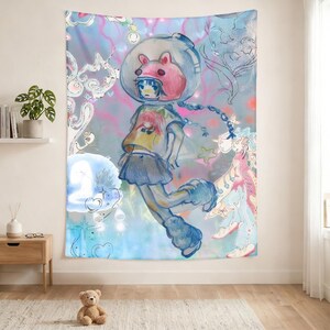 Op de afbeelding: Een grote wandtapijt met een kleurrijke illustratie van een meisje in een ruimtehelm met een roze beerachtig ontwerp. Het kunstwerk heeft een grillige stijl met pastelkleuren en zwevende elementen.