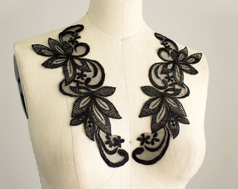 May include: Two black lace appliques with floral designs. The appliques are made of delicate black lace and feature intricate floral patterns. They are perfect for adding a touch of elegance to any garment.