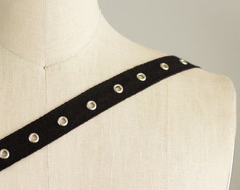 May include: Black cotton webbing with silver grommets. The webbing is on a white mannequin.