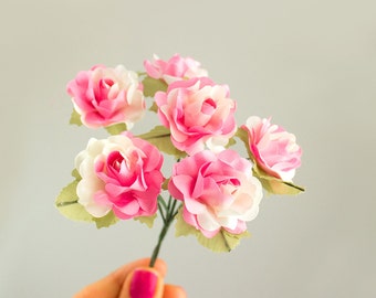 May include: A bouquet of six pink and white fabric roses with green leaves.
